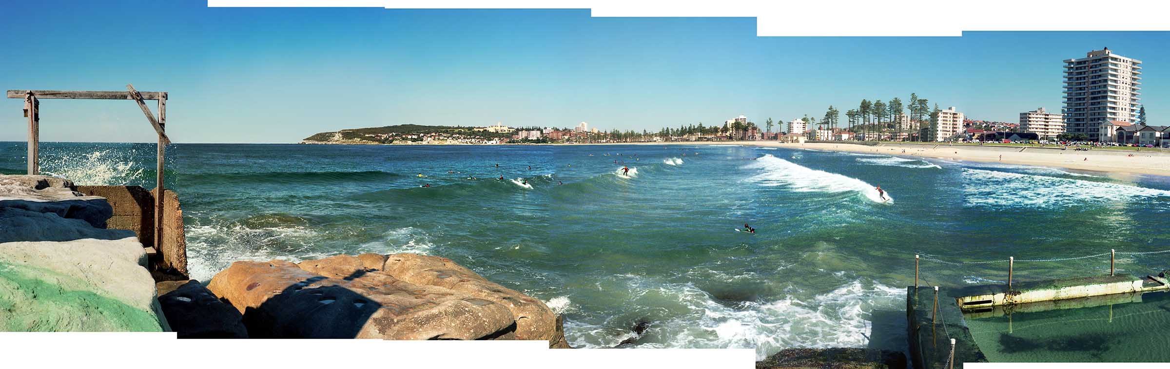 View of Manly Beach from the Queenscliff Headland with surfers catching waves in their wet suits.