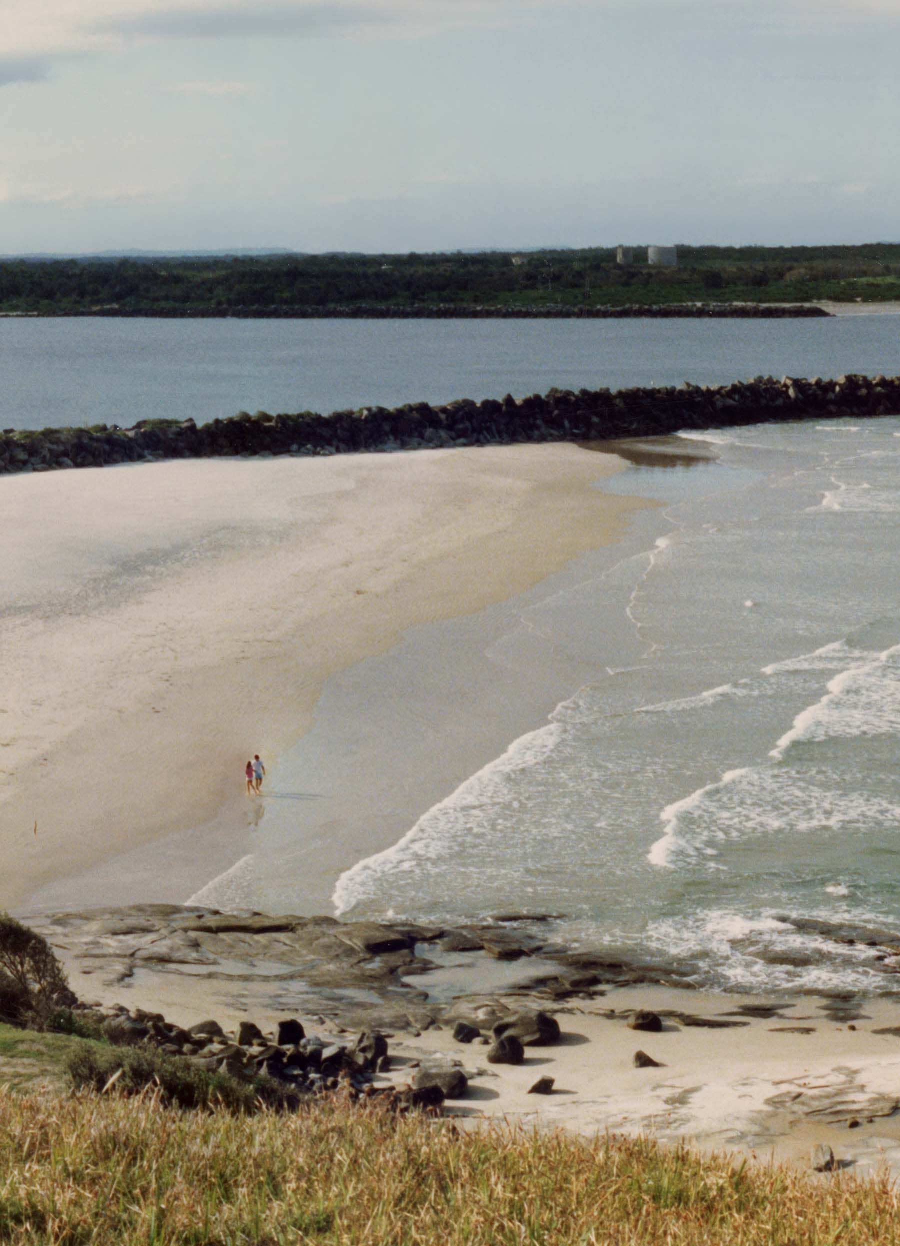 View of a couple enjoying the Yamba Headland beach and surf.